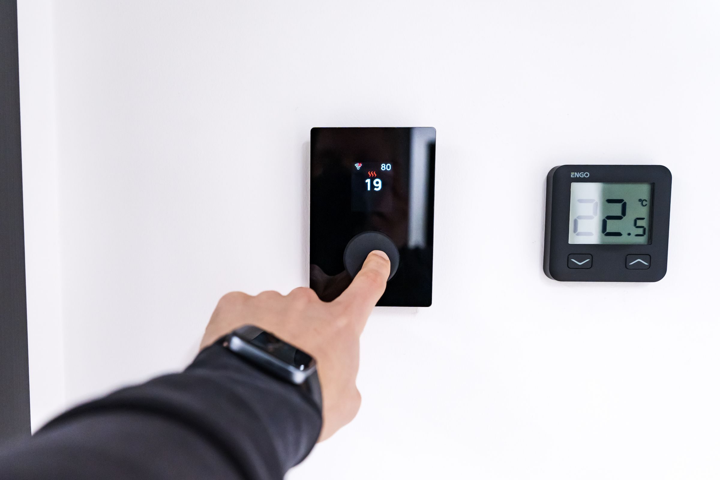 Main réglant un thermostat mural